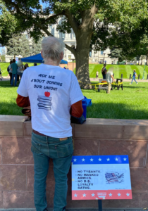 Back of man's t-shirt that says, "Ask me about joining our union!" Sign on the ground says, ""No Tyrants.  No masked armies. No B.S. loyalty oaths"