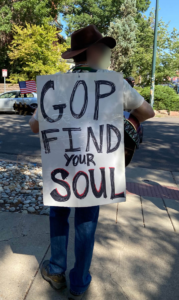 Person with sandwich board sign that says, "GOP find your soul"