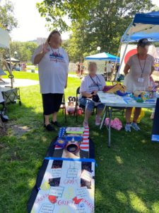 Indivisible staff members standing next to the corn hole board decorated to look like Donald Trump's open mouth.